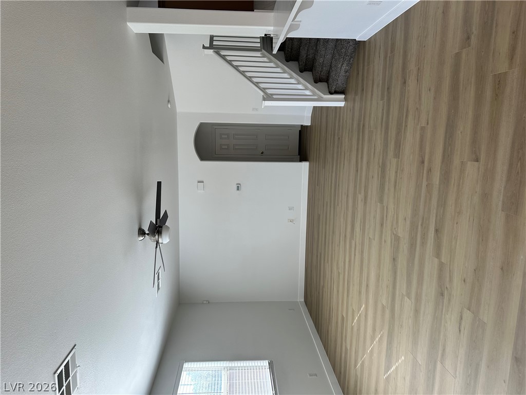 9639 West Post Road Las Vegas, NV 89148 - Photo 6 of 30 An open living space features durable wood-look flooring and a nearby carpeted staircase.