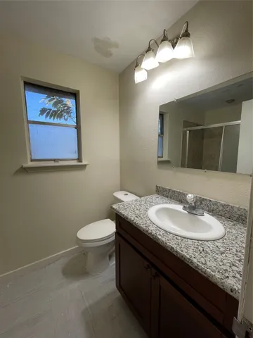 a bathroom with a granite countertop toilet a sink and a mirror