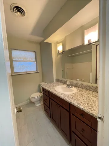 a bathroom with a granite countertop sink toilet and mirror