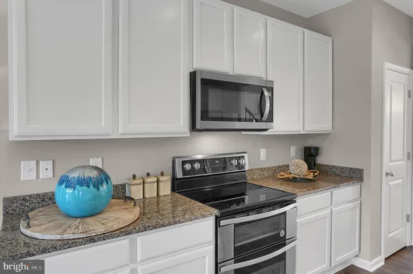 a kitchen with granite countertop white cabinets and stainless steel appliances