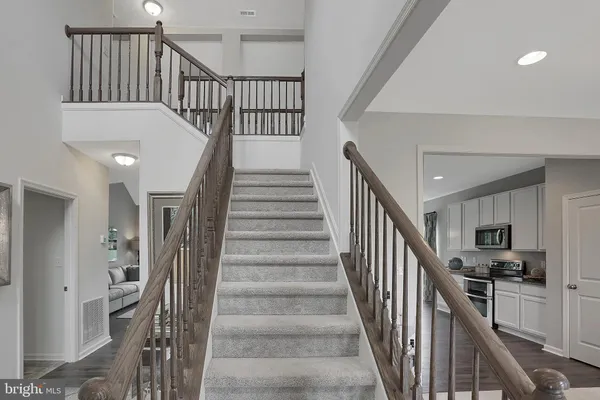 a view of staircase and kitchen with wooden floor and pendant lights