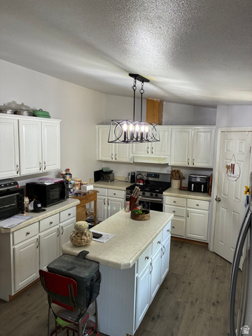547 East 2000th Street North Vernal, UT 84078 - Photo 3 of 50 Kitchen featuring white cabinetry, light countertops, wood-finish flooring, a center island with storage, and a stainless steel gas range