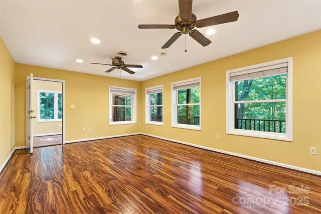 a view of an empty room with a window and wooden floor
