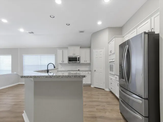 a kitchen with stainless steel appliances granite countertop a refrigerator and a sink