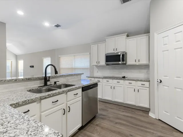 a kitchen with granite countertop white cabinets and stainless steel appliances