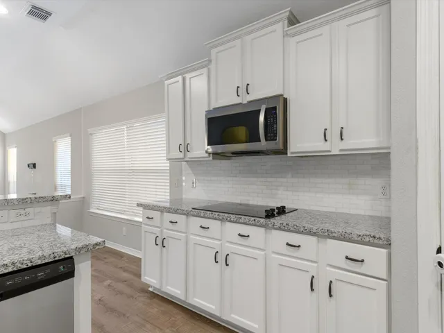 a kitchen with granite countertop white cabinets and a sink