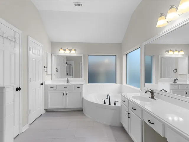 a bathroom with a tub a double vanity sink and mirror