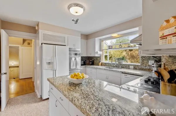 a kitchen with a stove a refrigerator and a view of living room