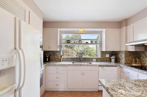 a kitchen with granite countertop a sink stainless steel appliances and cabinets