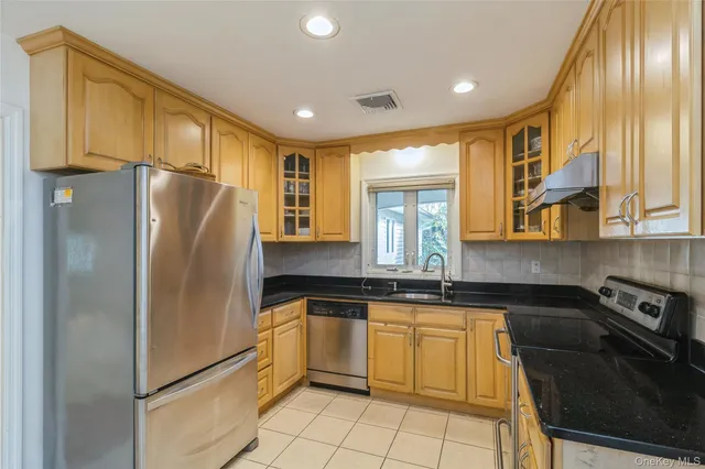 a kitchen with granite countertop stainless steel appliances a refrigerator and cabinets