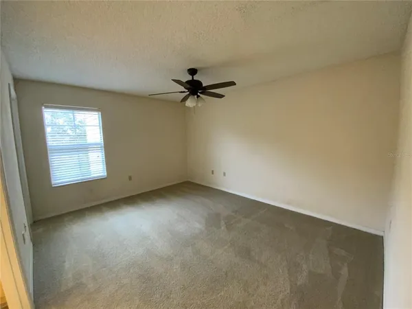 an empty room with a window and a ceiling fan