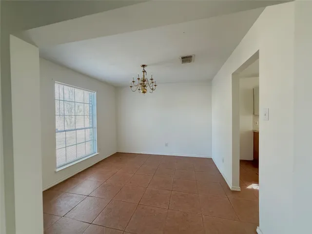 an empty room with windows and chandelier fan