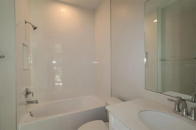 a bathroom with a granite countertop sink a toilet and shower