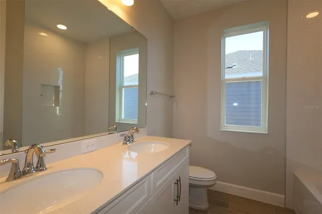 a bathroom with a granite countertop sink toilet and large mirror
