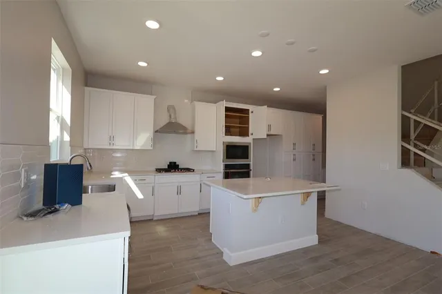 a kitchen with stainless steel appliances a sink a stove a microwave a refrigerator and cabinets