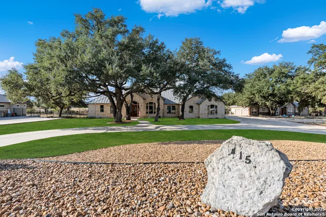 a front view of a house with a garden and trees