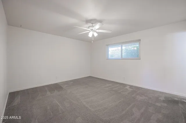 an empty room with windows and fan
