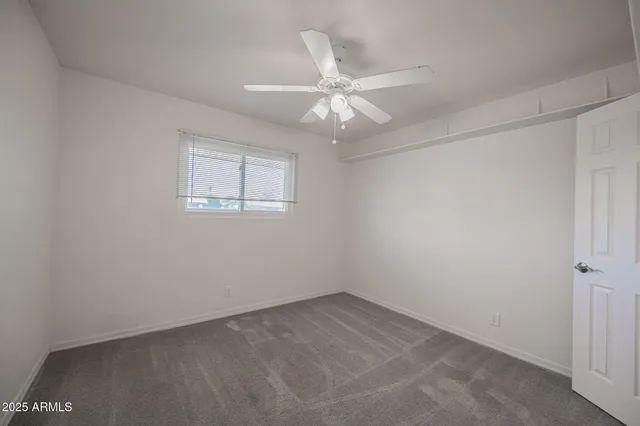 an empty room with a window and a fan