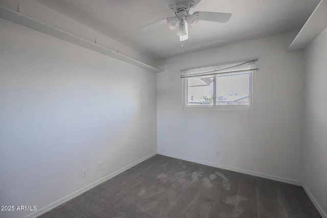 an empty room with a chandelier fan and windows