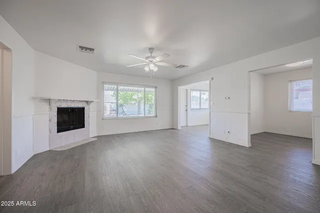 an empty room with windows chandelier fan and windows