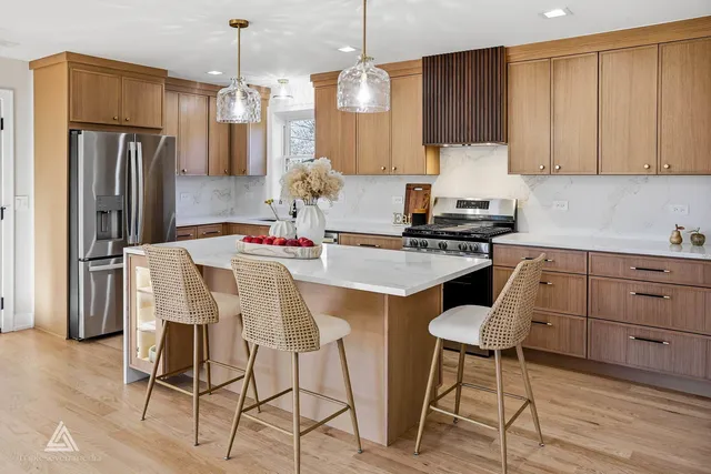 a kitchen with stainless steel appliances kitchen island granite countertop a refrigerator a stove a sink and white cabinets with wooden floor