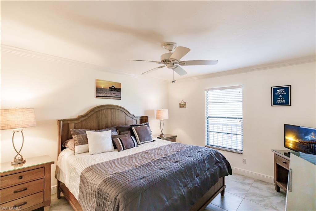 600 Neapolitan Way, Unit 454 Naples, FL 34103 - Photo 11 of 26 a bedroom with a bed and a flat tv screen on dresser