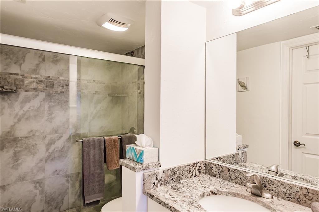 600 Neapolitan Way, Unit 454 Naples, FL 34103 - Photo 14 of 26 a bathroom with a granite countertop sink and a mirror