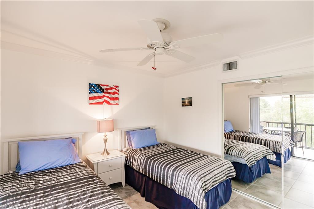 600 Neapolitan Way, Unit 454 Naples, FL 34103 - Photo 16 of 26 a bedroom with a bed and a chandelier