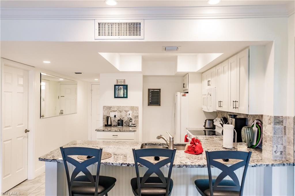 600 Neapolitan Way, Unit 454 Naples, FL 34103 - Photo 7 of 26 a view of kitchen with cabinets and wooden floor