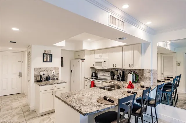 a kitchen with stainless steel appliances kitchen island granite countertop a sink refrigerator and cabinets