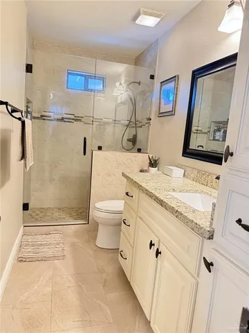 a bathroom with a granite countertop sink mirror vanity and toilet