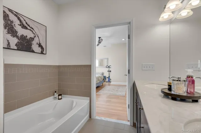 a bathroom with a tub sink and mirror