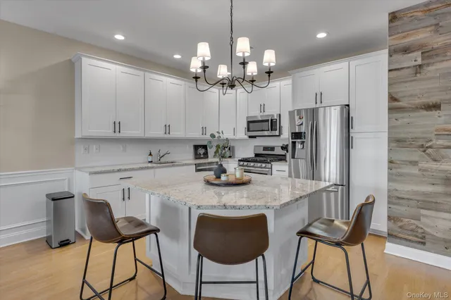 a kitchen with stainless steel appliances kitchen island granite countertop a dining table chairs and a refrigerator
