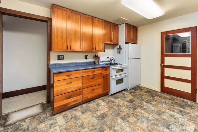 a kitchen with granite countertop a stove a sink and a refrigerator