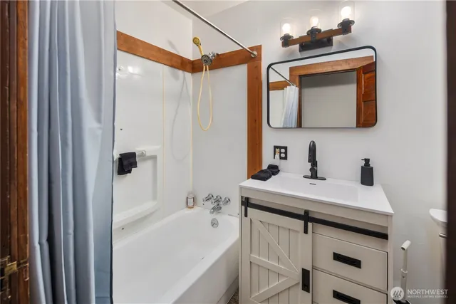 a bathroom with a sink vanity granite tub shower and a mirror