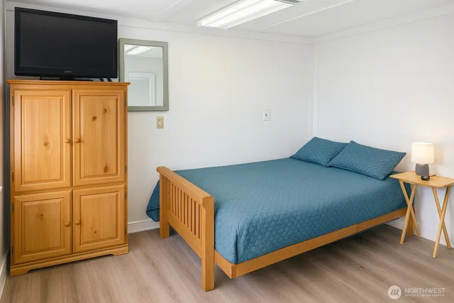 a bedroom with a bed and flat tv screen on the dresser