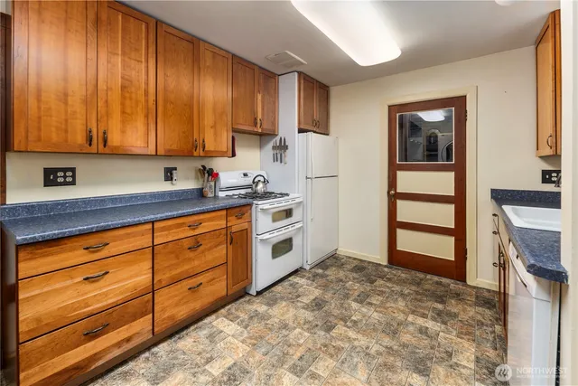 a kitchen with granite countertop wooden cabinets and white appliances