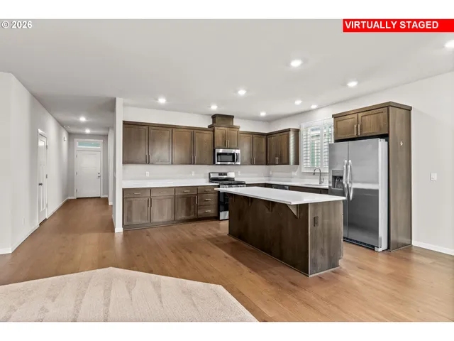 a kitchen with stainless steel appliances granite countertop a refrigerator a sink a stove and oven