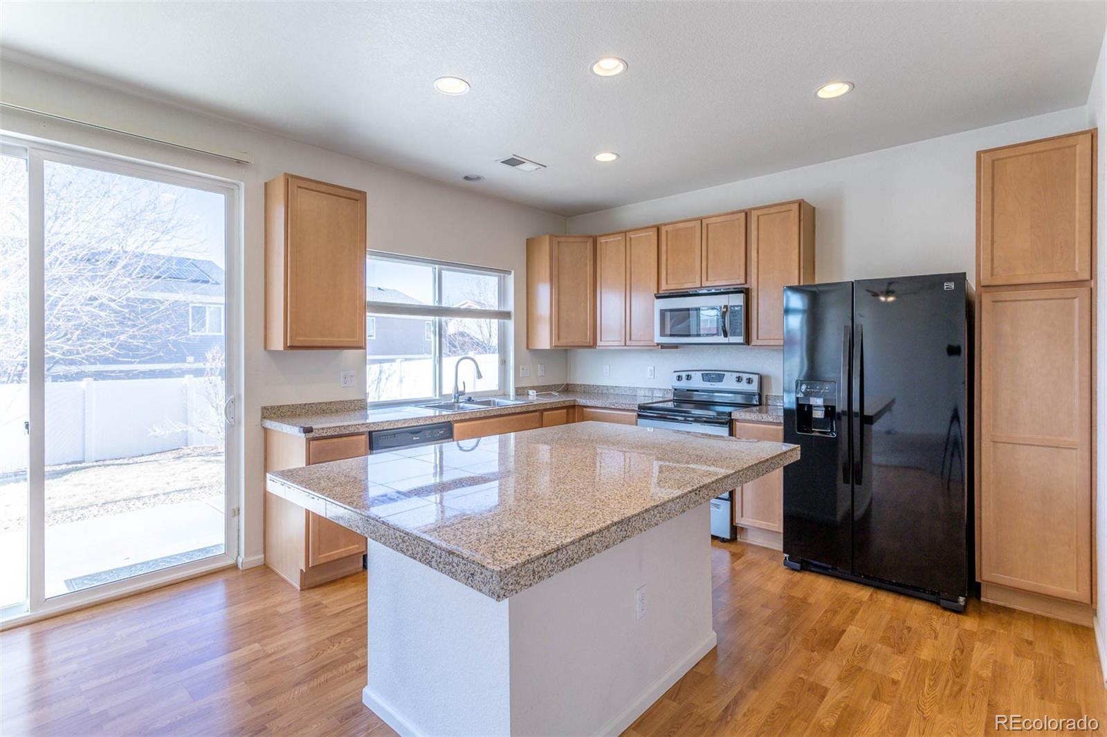 5559 Malta Street Denver, CO 80249 - Photo 4 of 27 a kitchen with a refrigerator a sink dishwasher and a stove with wooden floor