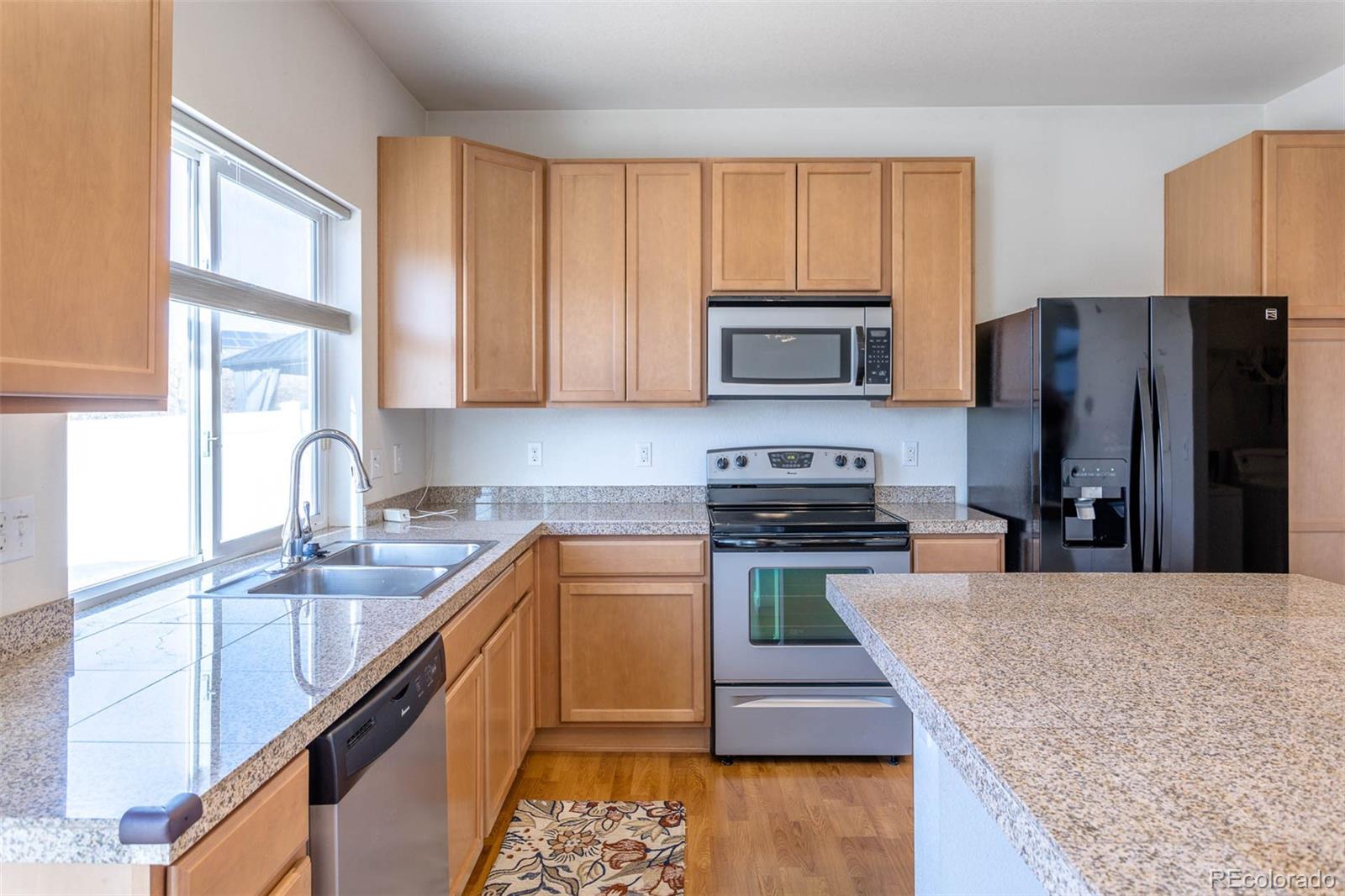 5559 Malta Street Denver, CO 80249 - Photo 7 of 27 a kitchen with stainless steel appliances granite countertop a stove top oven a sink dishwasher a refrigerator and a microwave