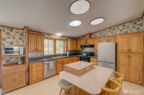 a kitchen with sink refrigerator dining table and chairs