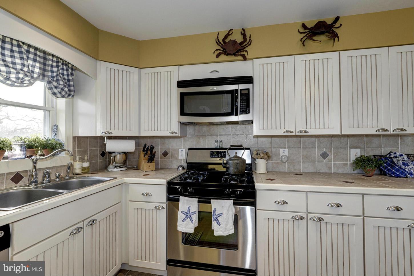 4940 Skinners Neck Road Rock Hall, MD 21661 - Photo 13 of 30 a kitchen with stainless steel appliances granite countertop white cabinets a stove a sink and dishwasher