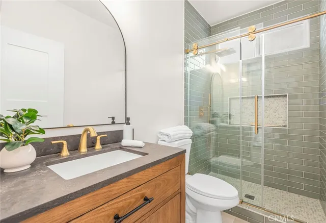a bathroom with a granite countertop sink a toilet and shower