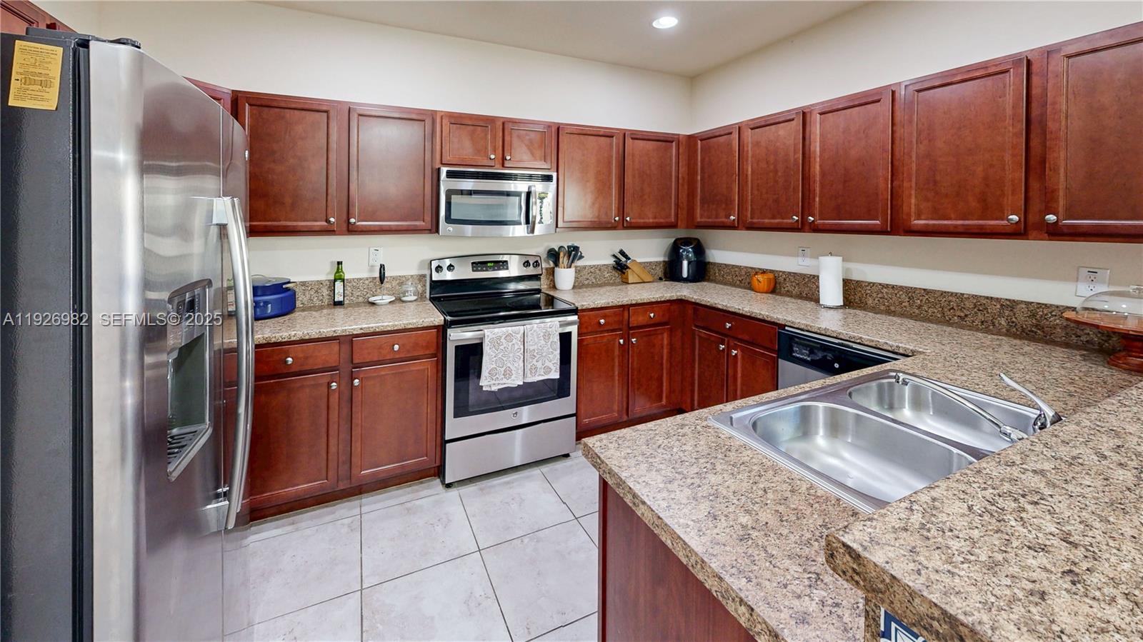 3218 Southeast 5th Court Homestead, FL 33033 - Photo 18 of 68 a kitchen with stainless steel appliances granite countertop a sink stove microwave and refrigerator