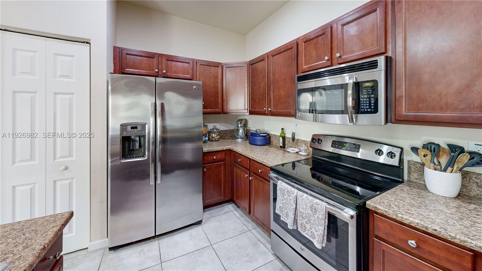 3218 Southeast 5th Court Homestead, FL 33033 - Photo 19 of 68 a kitchen with stainless steel appliances granite countertop a refrigerator a stove and a sink with wooden cabinets