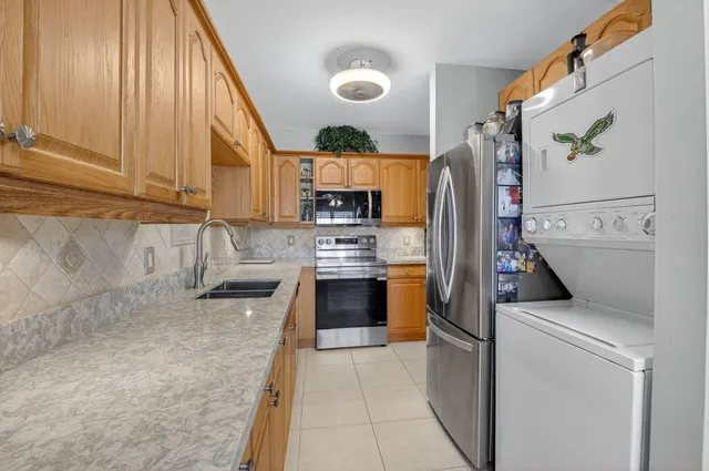a kitchen with stainless steel appliances granite countertop a refrigerator a stove and a sink with wooden floor
