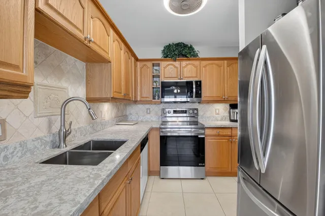 a kitchen with stainless steel appliances granite countertop a refrigerator a sink a stove a microwave and cabinets