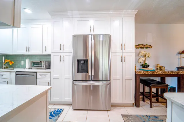a kitchen with a refrigerator a stove a sink and white cabinets