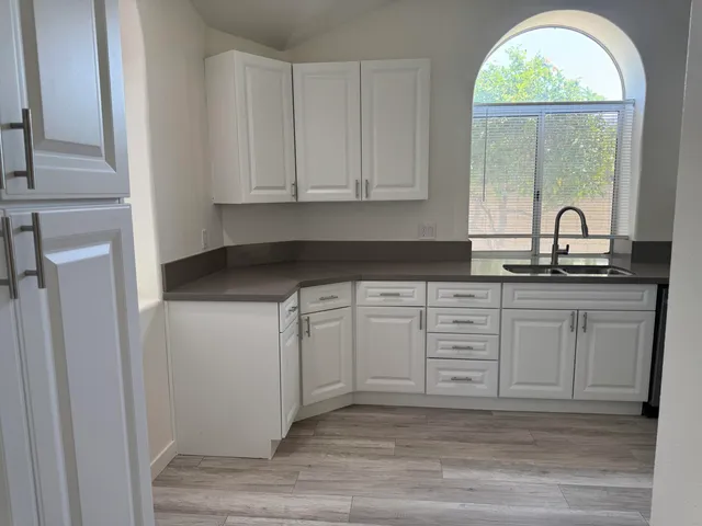 a kitchen with granite countertop white cabinets and wooden floor