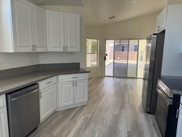 a kitchen with stainless steel appliances wooden floor sink and wooden cabinets